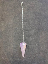 Purple amethyst stone pendulum with a pointed faceted shape attached to a silver chain laid flat on a dark textured surface.