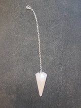 Pale pink faceted stone pendulum attached to a fine silver chain with a small ring at the end, on a textured dark gray background.