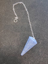 Blue stone pendulum with a conical shape attached to a silver chain with a ring on a dark textured surface