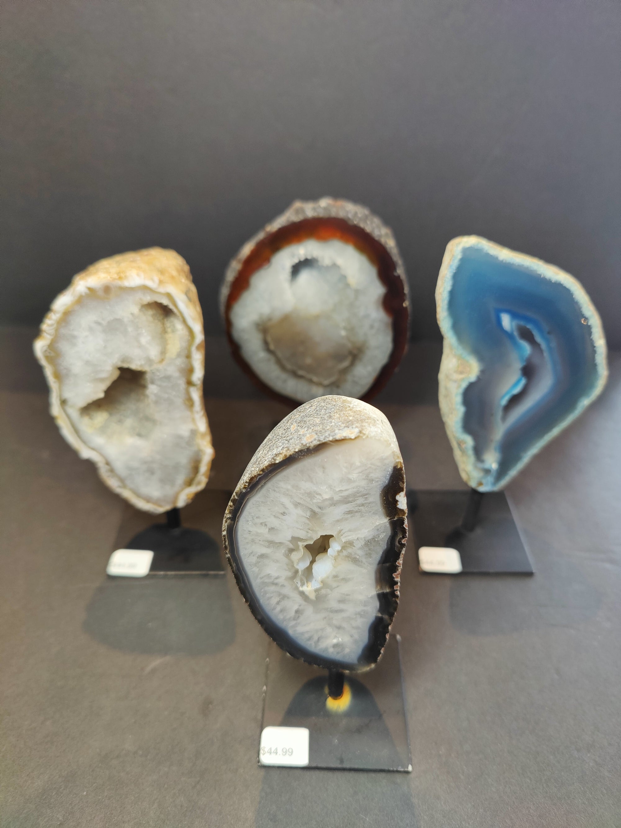 Polished agate geode displayed on a metal stand, showing the natural texture and layered colors of the stone