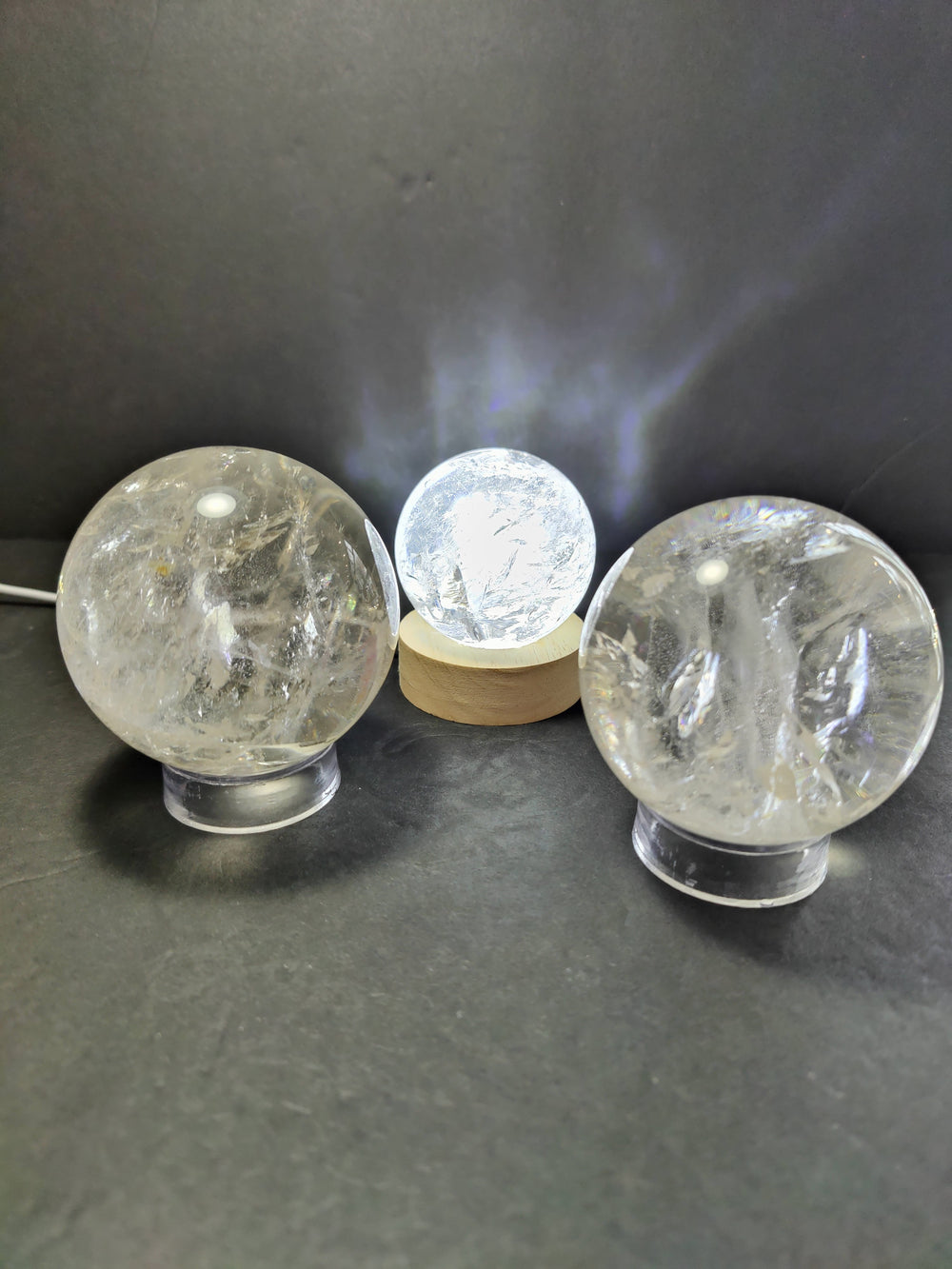 Clear Quartz polished spherical sculpture on a black stand with a light blue gradient background