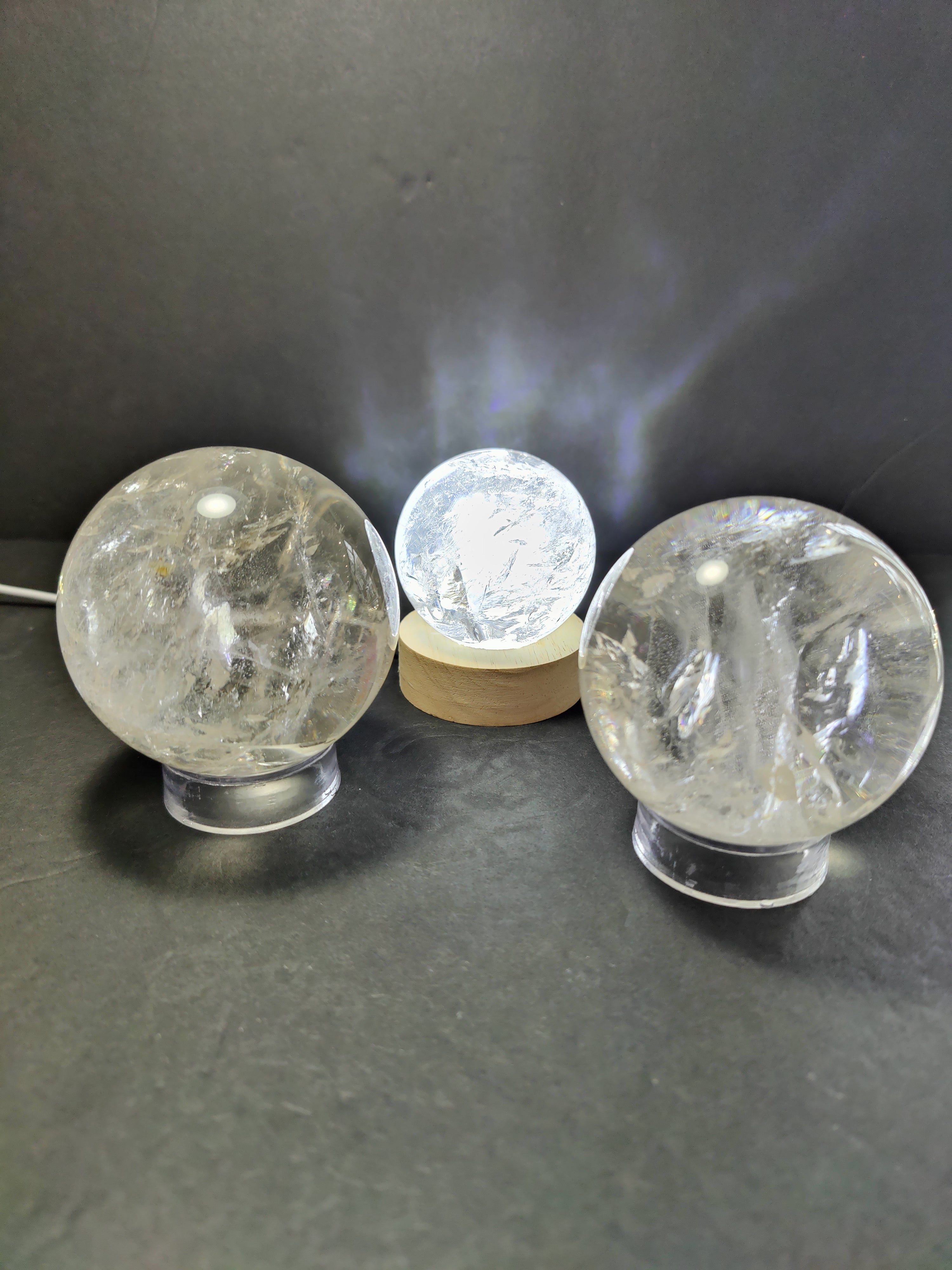 Clear Quartz polished spherical sculpture on a black stand with a light blue gradient background