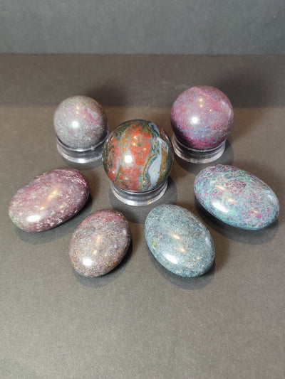 Ruby Kyanite polished spheres and palmstones in a display