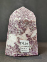 Polished lepidolite obelisk tower with purple and white crystalline patterns and a pointed top, labeled with price and country of origin stickers.