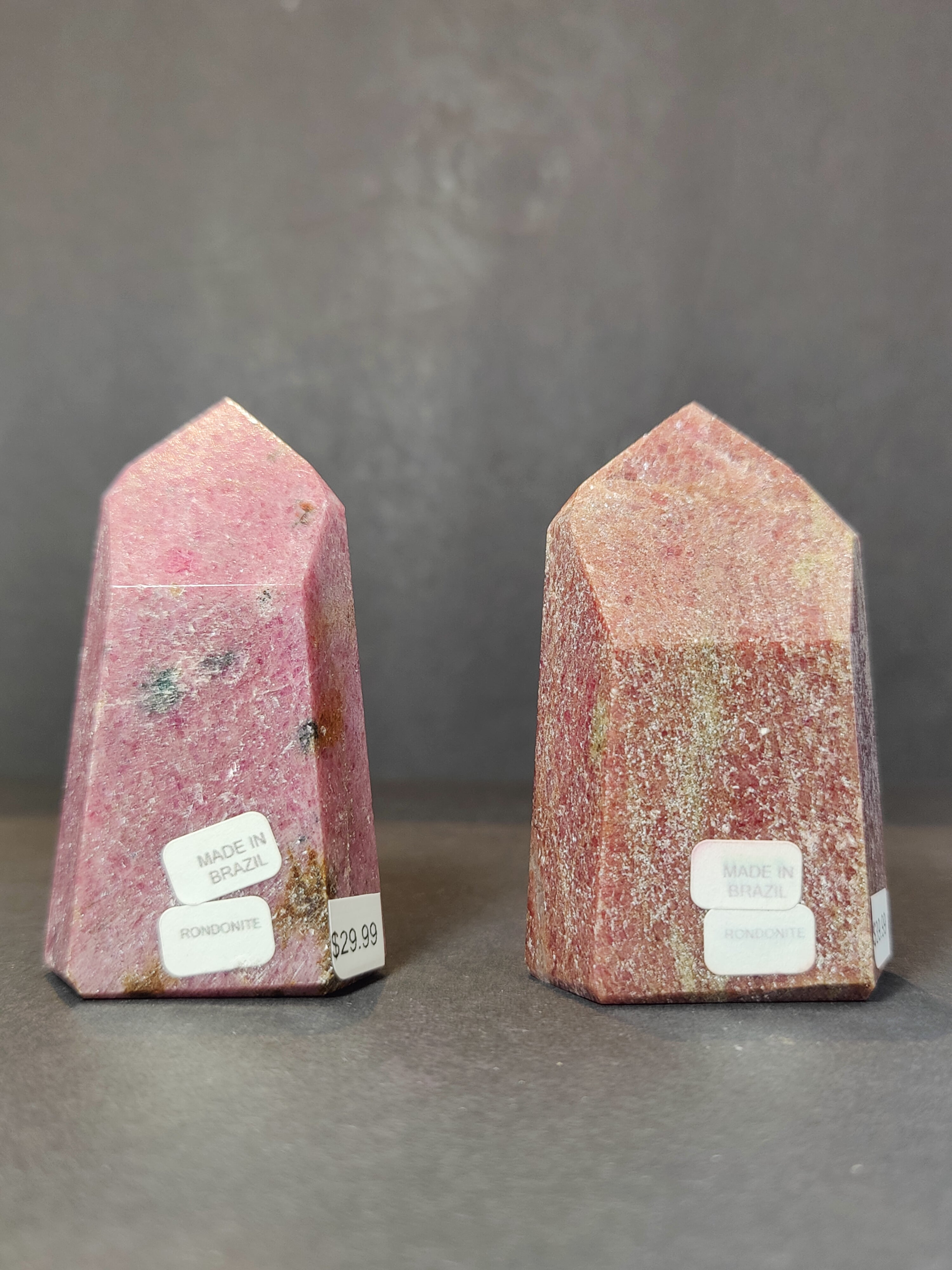 Polished Rhodochrosite obelisk tower sculpture with pink and white mineral patterns on light background