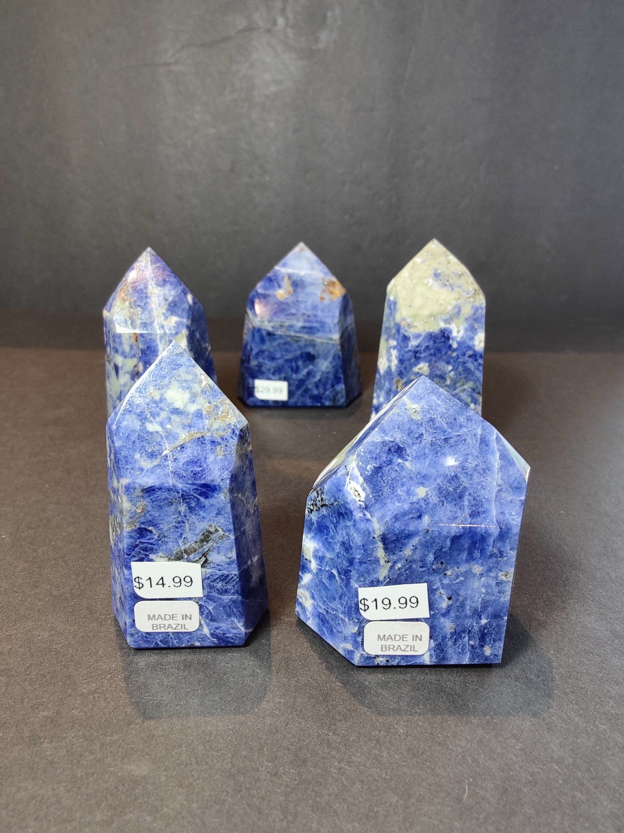 Polished blue sodalite obelisk tower sculpture on a white surface