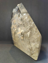 Polished natural citrine crystal point with clear golden-yellow hues and visible internal fractures, standing upright against a dark background.