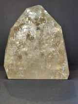 Polished natural citrine crystal in a pointed shape with a translucent golden hue and internal fractures reflecting light on a dark background.