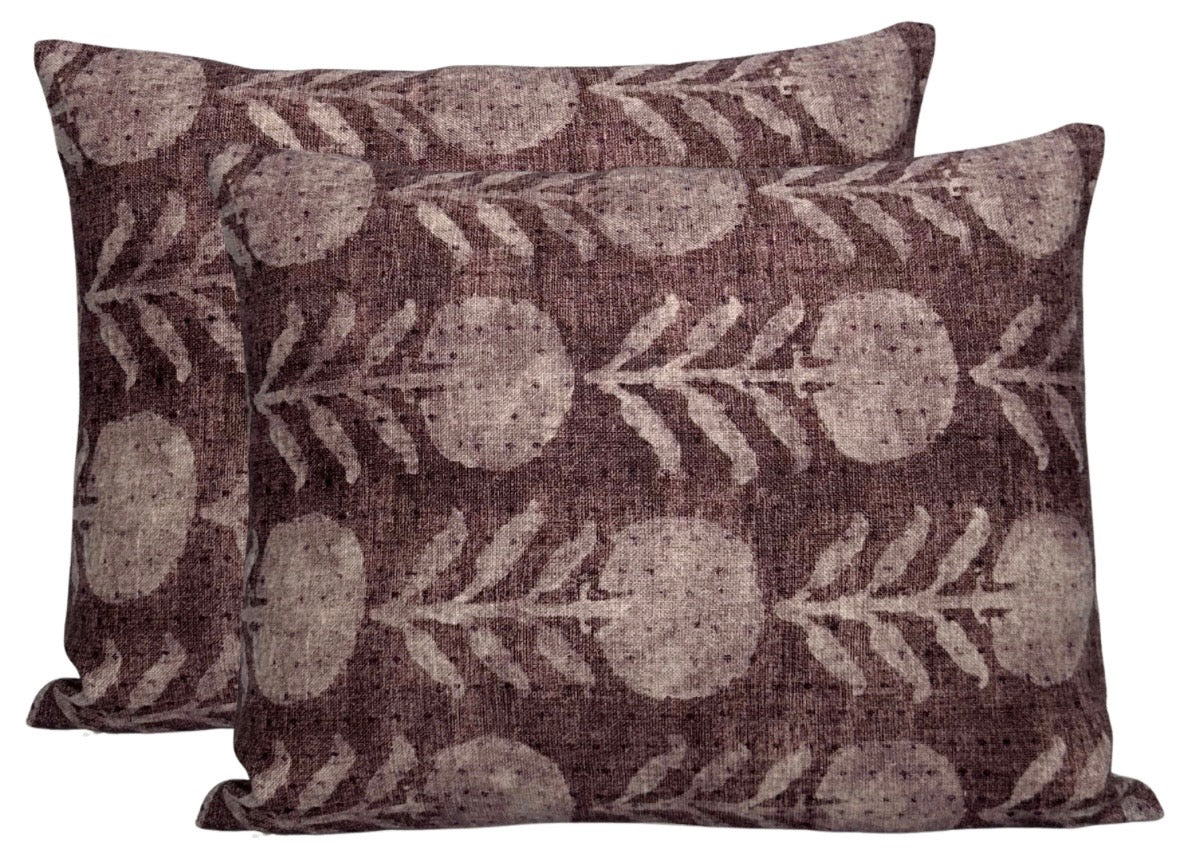 Two rectangular berry-colored pillow covers with a repeating light gray zinnia flower and leaf pattern on textured fabric.