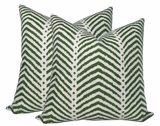 Pair of square pillow covers with a white background and a green zigzag chevron pattern, shown upright and slightly overlapping.
