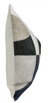 Side view of a rectangular pillow with a modern color-block pattern featuring large curved and square shapes in shades of black, gray, and beige on a woven fabric cover.