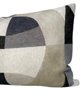 Rectangular pillow with overlapping rounded shapes in shades of black, gray, beige, and olive creating a modern abstract pattern.