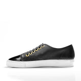 Black low-top leather sneaker with glossy leather toe cap, gold eyelets, and white rubber sole, shown from the side on a white background.