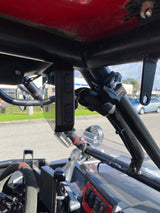 Black TrailVue camera mounted on a black roll cage bar inside a vehicle, with a visible clamp and two buttons on the camera housing.