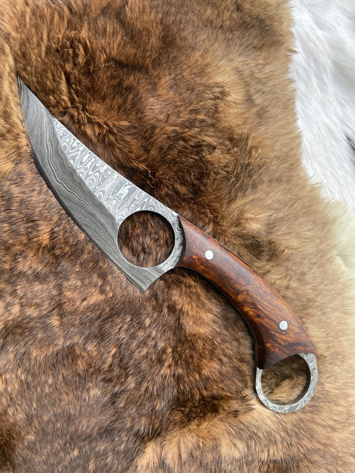 Close-up of the Damascus blade and handle of the Titan Knives Skinner TK-059, showing layered steel pattern and ergonomic handle