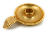 Textured golden circular candlestick holder dish with a small leaf-shaped handle on one side, designed to hold a single taper candle.