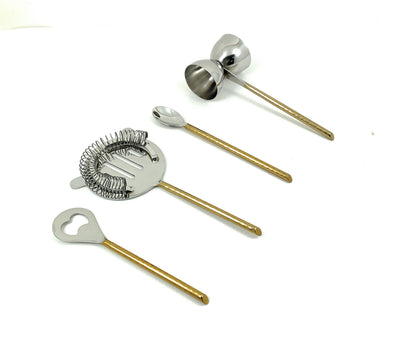 Vibhsa bar tools set with flat opener, jigger, stirring spoon, and martini shaker in golden hammered finish arranged on a dark surface