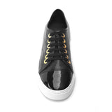 Black leather sneaker with a shiny black patent leather toe, photographed on a neutral background.