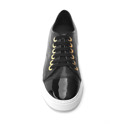 Black leather sneaker with a shiny black patent leather toe, photographed on a neutral background.