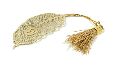 Set of six golden brass feather bookmarks with satin tassels laid out on a wooden surface