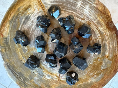 Medium Melanite Garnet mineral specimen from Mali, Africa, shown in natural lighting on a wooden surface