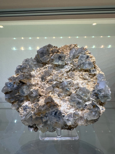 Blue translucent cubic Fluorite cluster resting on natural matrix, showing vivid blue cubic crystals