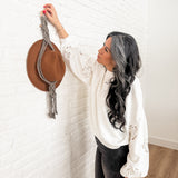 Macrame hat hanger single in natural color hanging on a wall displaying a hat
