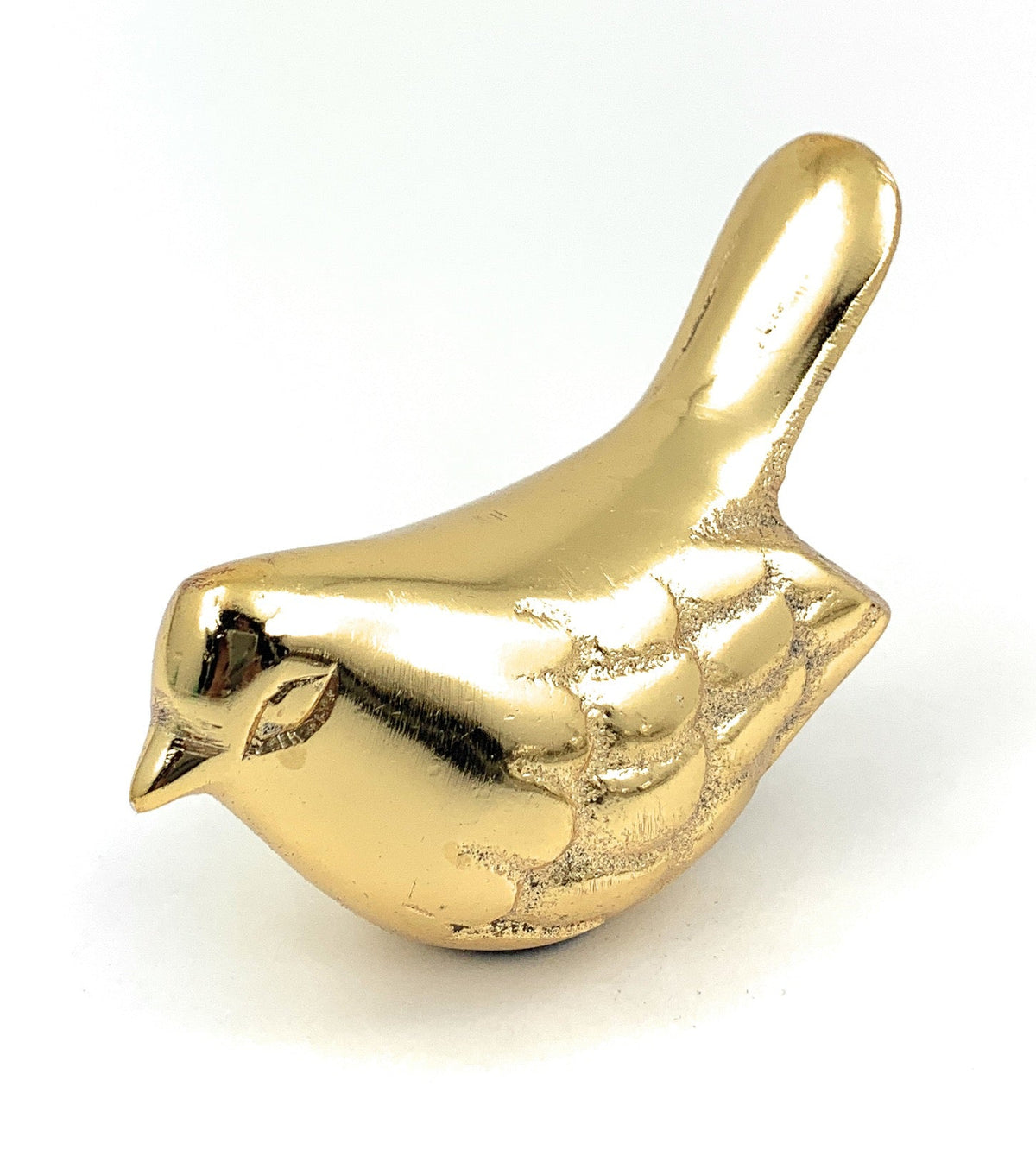 Small golden bird figurine with detailed wing etchings and a smooth tail, positioned facing left on a white background.