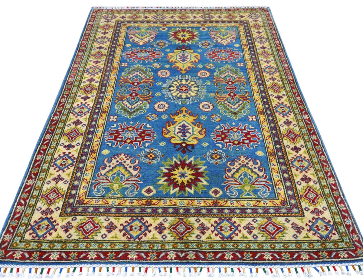 Rectangular hand-knotted Afghani Kazak rug with blue central field featuring colorful geometric motifs and multiple cream, red, and yellow patterned borders with fringed edges.