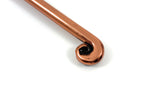 Close-up of a copper-finished appetizer fork tip with a curled end detail against a white background.