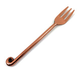 Copper-finish appetizer fork with a three-prong head and a long handle ending in a curled detail, shown on a white background.