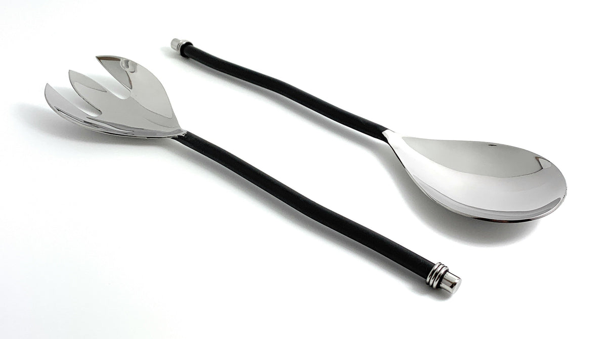 Pair of silver-finish salad serving utensils with long, black twisted handles, including a slotted fork and a solid spoon, shown on a white background.