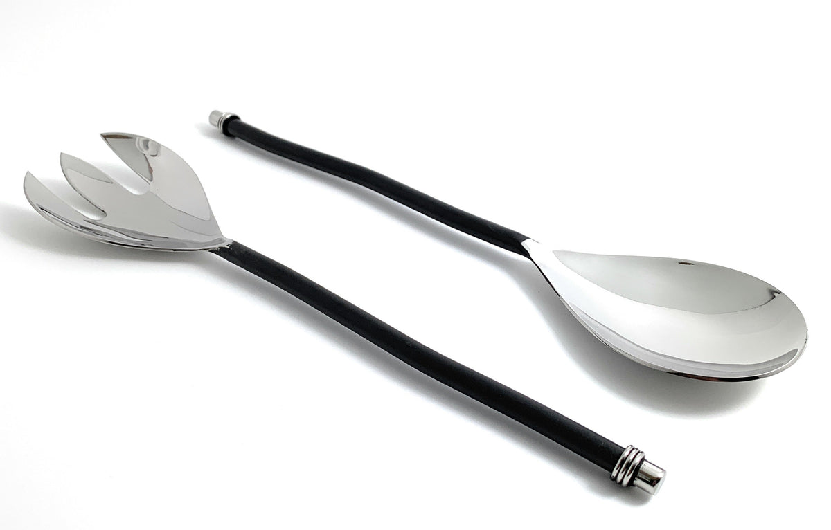 Pair of salad serving utensils with twisted black handles and shiny silver finish, featuring a slotted fork and solid spoon, displayed on a white background.