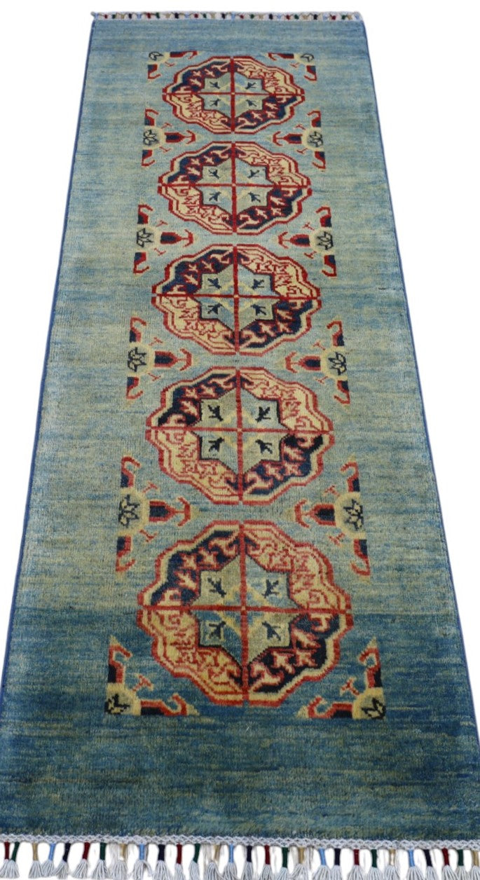 Runner rug with a blue gradient background featuring a central column of five geometric medallions in red, beige, and navy, with corner motifs and a fringed edge.
