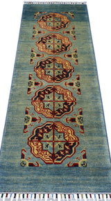 Long rectangular Afghani Kazak wool rug with a muted blue-green field and repeating hexagonal medallions in cream, red, brown, and black, finished with white fringe.
