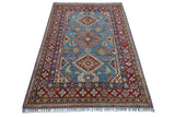 Hand-knotted Afghani Kazak wool rug with a blue central field featuring diamond medallions and a red geometric border with floral motifs and fringed edges.