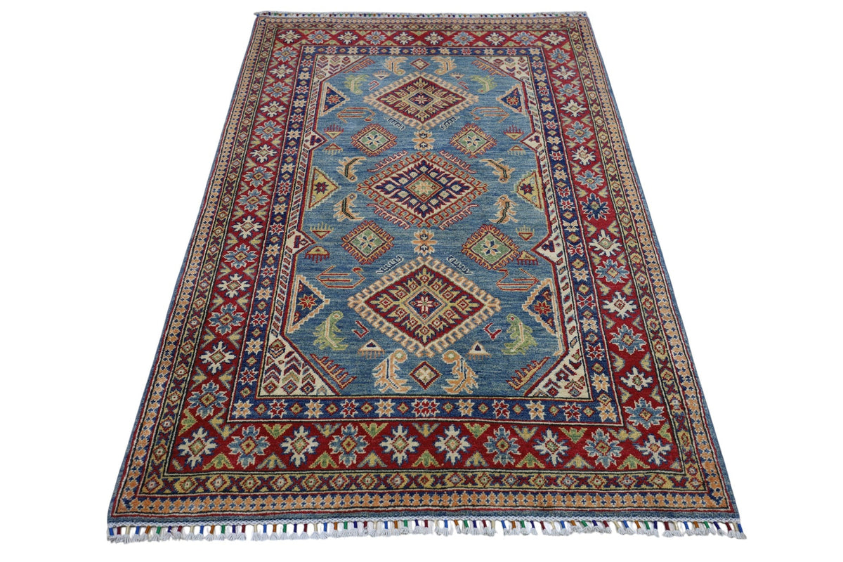 Hand-knotted Afghani Kazak wool rug with a blue central field featuring diamond medallions and a red geometric border with floral motifs and fringed edges.