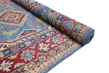 Partial view of a hand-knotted Afghani Kazak wool rug with red, blue, and beige geometric and floral patterns, partially rolled to show thickness and weave.