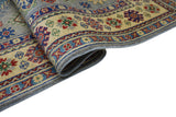 Close-up of a folded hand-knotted Afghani Kazak wool rug featuring floral and geometric patterns in red, blue, and green on a cream background with a blue border.
