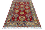 Rectangular Afghani Kazak wool rug with deep red field, geometric medallions, multi-colored floral motifs, and a wide beige and blue patterned border with fringe.
