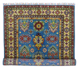 Rectangular hand-knotted Afghani Kazak wool rug with central blue field featuring intricate red, yellow, and green geometric floral motifs and a multi-layered cream and red ornate border.
