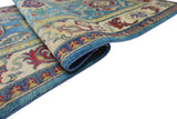 Close-up of a folded Afghani Kazak wool rug with a blue, red, and beige geometric pattern and a detailed border design.
