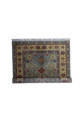 Hand-knotted Afghani Kazak wool rug with geometric central medallion in blue, red, and cream tones, bordered by intricate floral and star motifs.