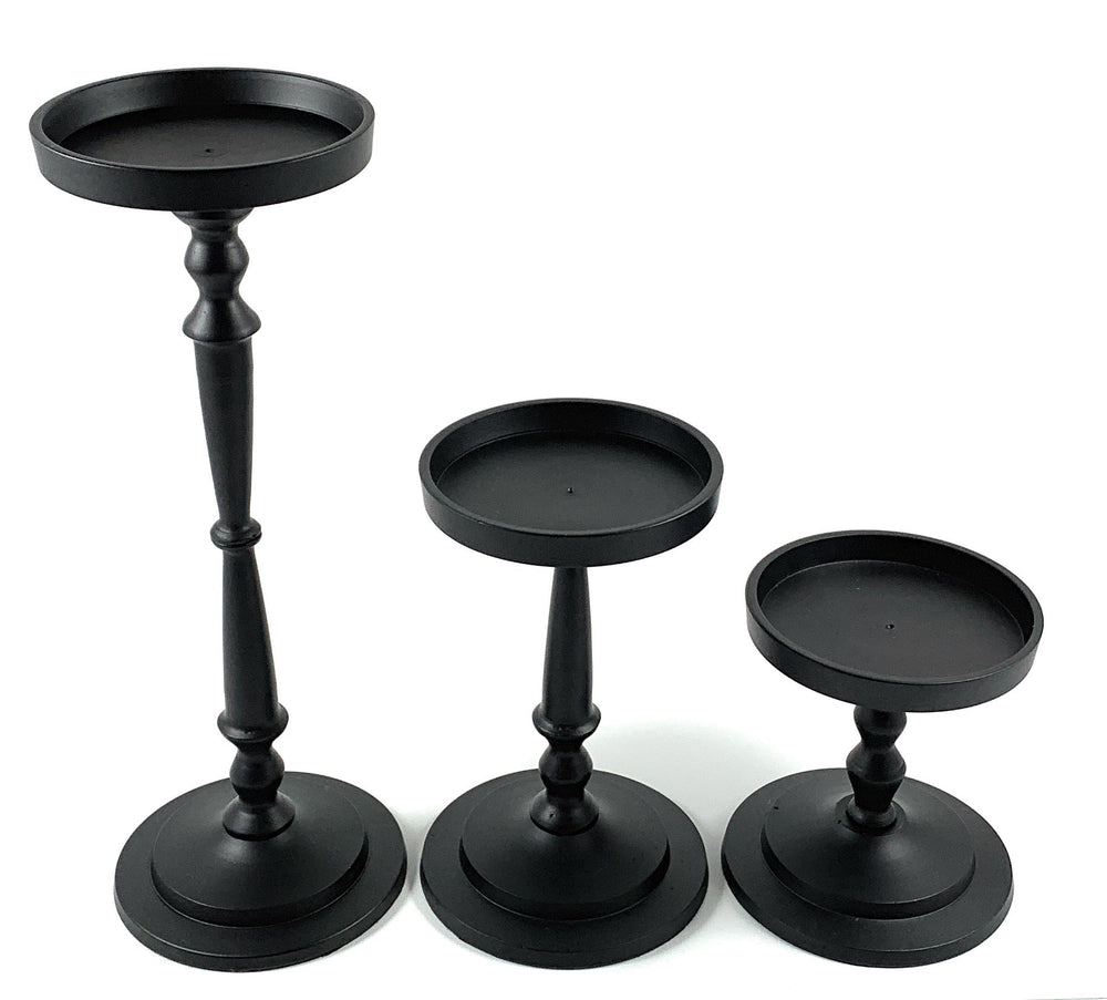 Set of three matte black pillar candle holders by Vibhsa in varying heights placed on a white tabletop