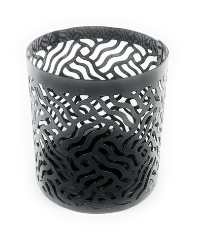 Two grey votive candle holders with laser cut patterns casting shadows