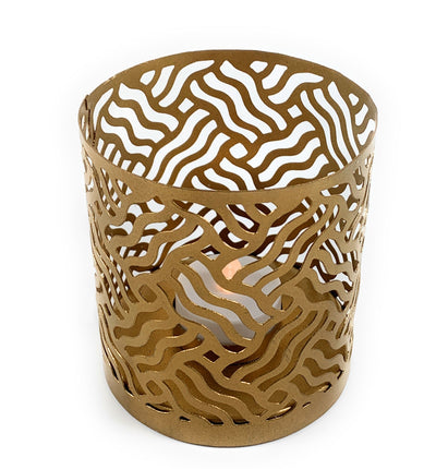 Two golden votive candle holders featuring intricate laser cut patterns casting shadows