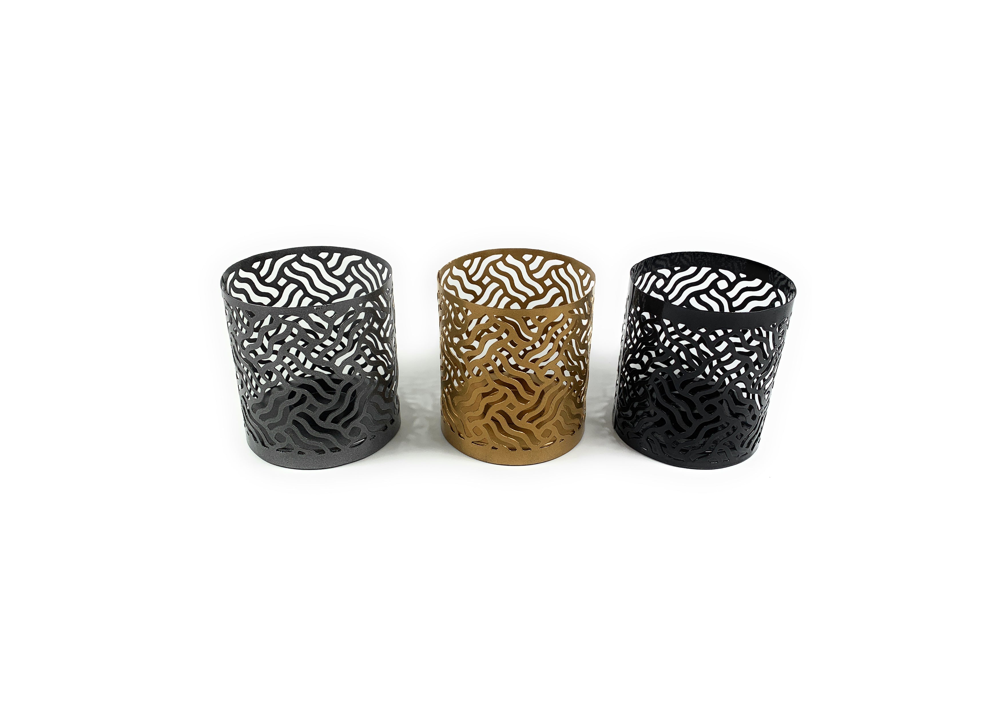 Set of three Vibhsa votive candle holders in black, grey, and golden colors arranged together