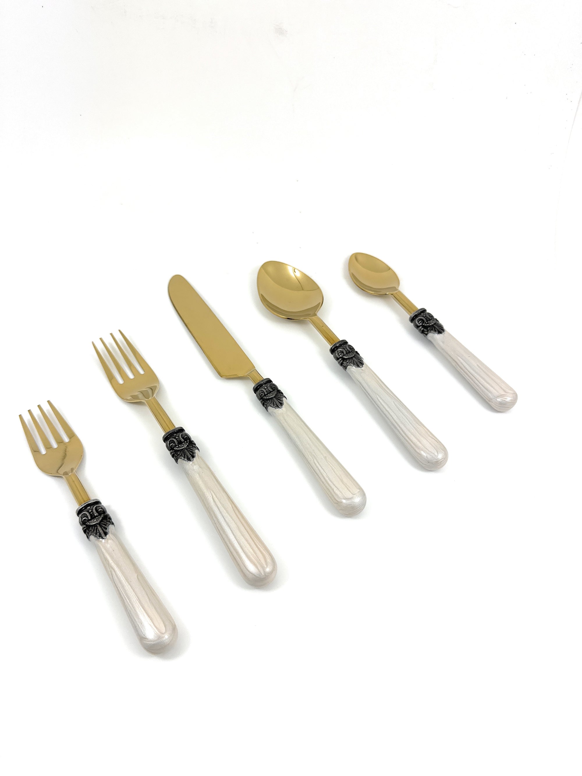 Set of white resin handle flatware including forks, knives, and spoons arranged on a cloth napkin with wine glasses nearby.