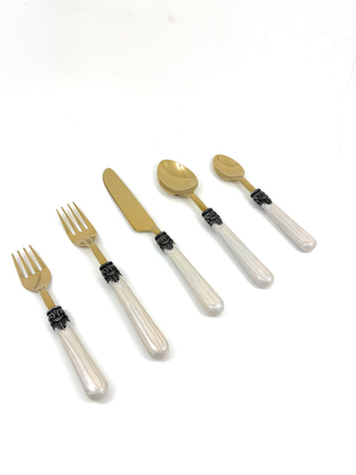Set of white resin handle flatware including forks, knives, and spoons arranged on a cloth napkin with wine glasses nearby.