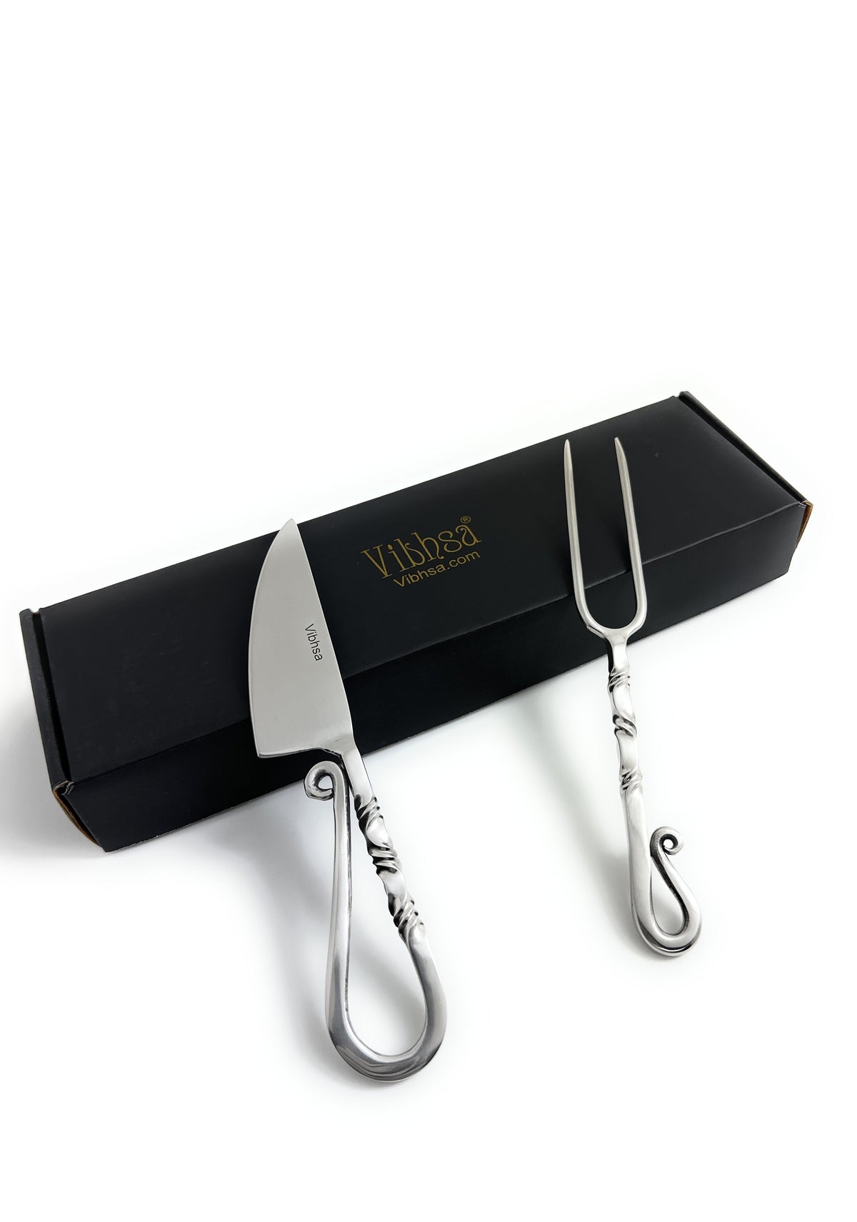 Stainless steel carving knife and fork set featuring sculpted handles with curled ends, displayed on a black box with gold branding.